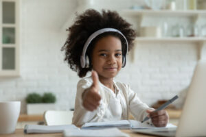 a young girl with a learning disability giving thumbs up during an online tutoring session