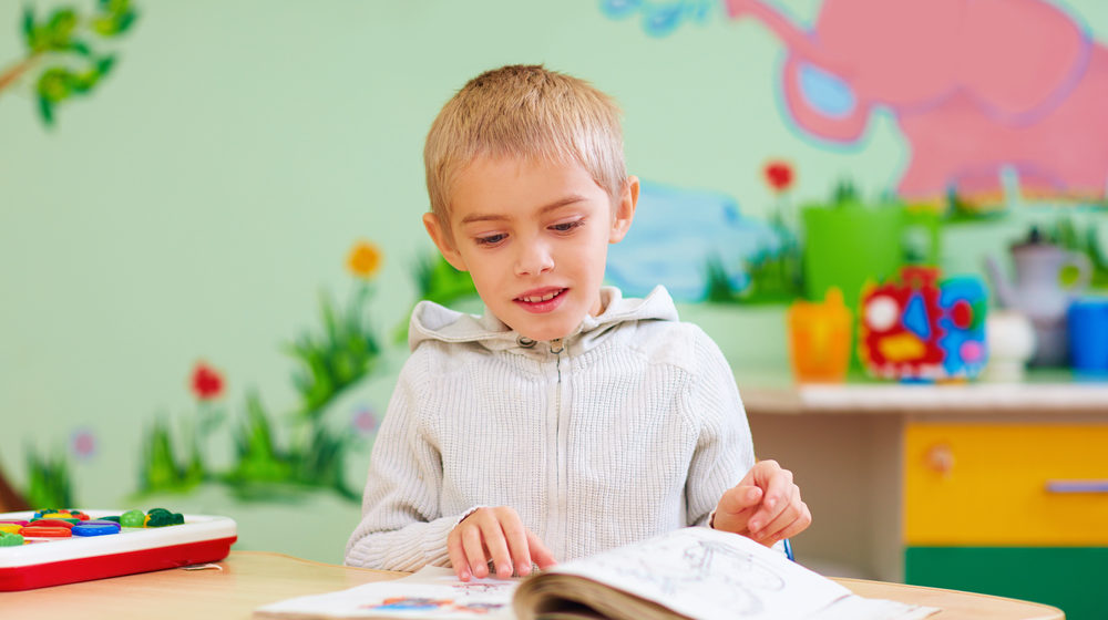 boy with autism reading with help of tutor