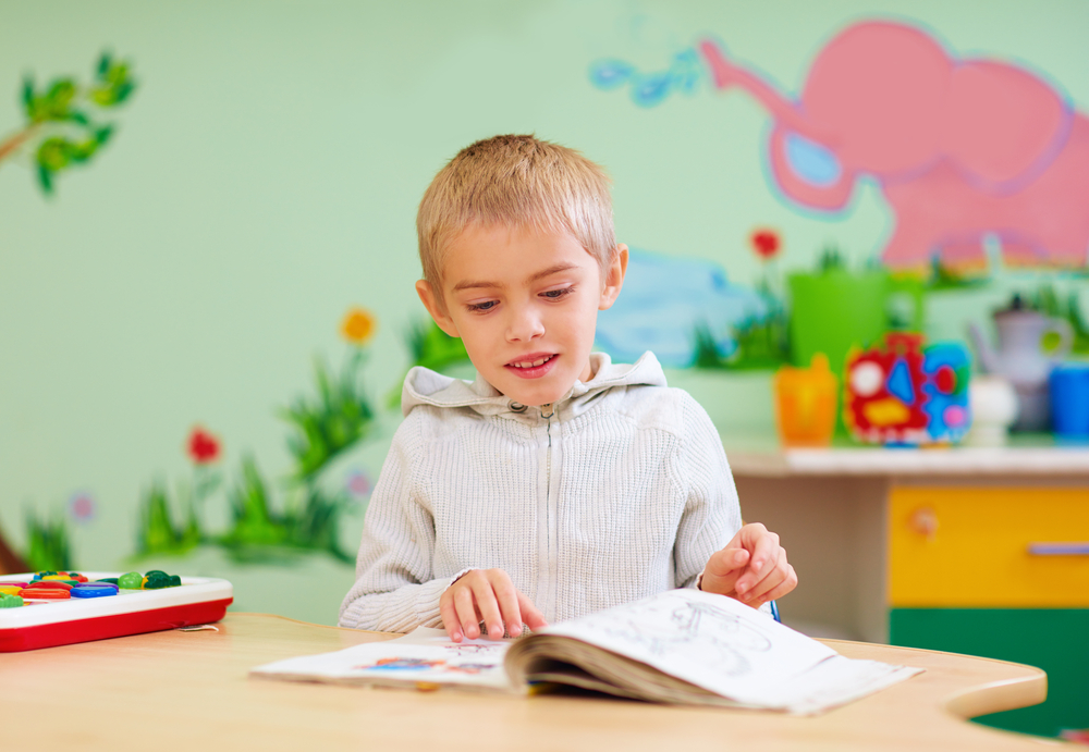 boy with autism reading with help of tutor